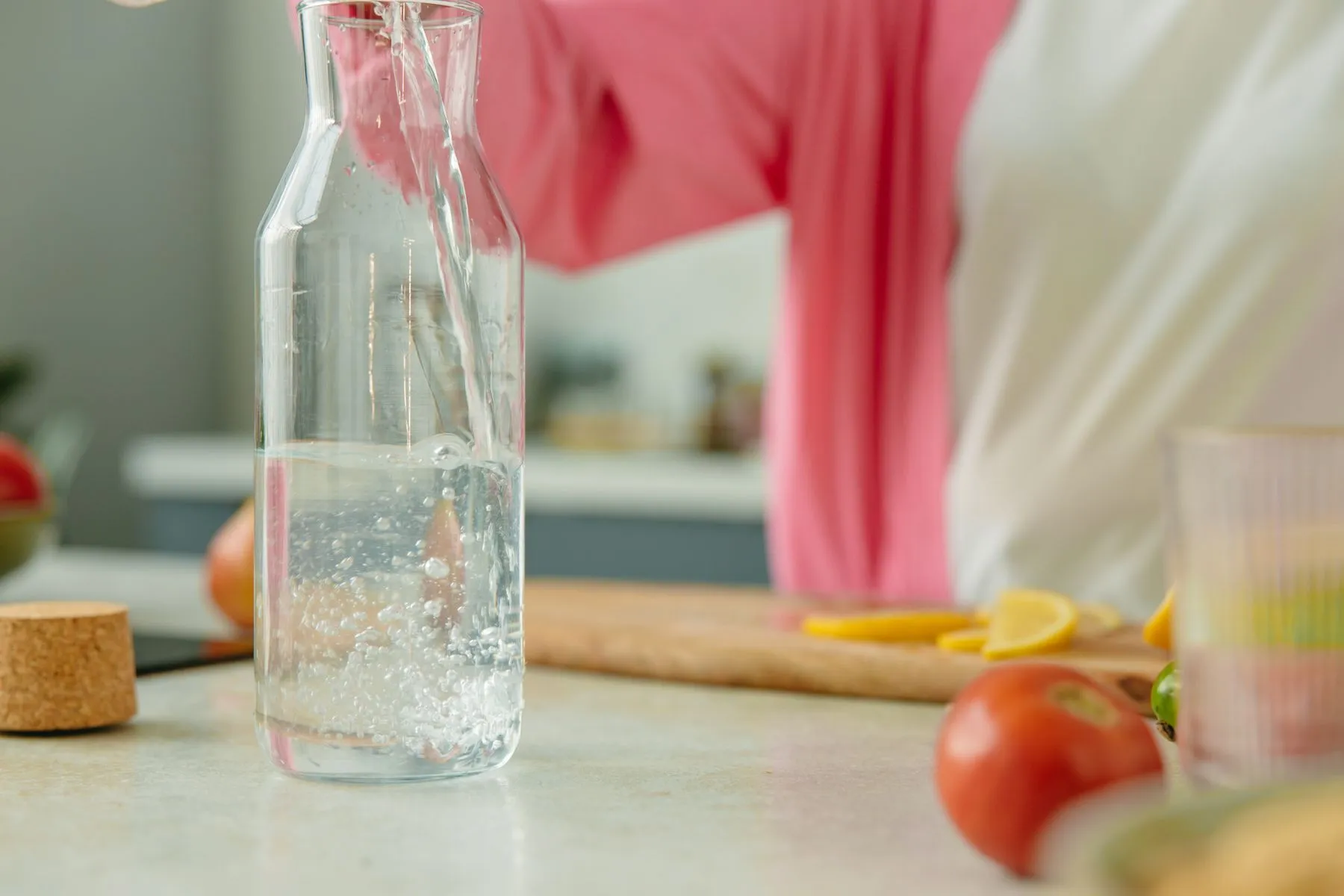 Jarra de agua y vasos preparados sobre una mesa luminosa